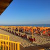 Spiaggia con file di ombrelloni arancioni.