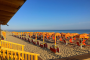 Spiaggia con ombrelloni e sedie a sdraio arancioni.