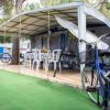 Tenda da campeggio con tavolo e sedie, bici davanti.