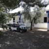 Casa bianca con veicolo parcheggiato e alberi.