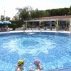 Piscina rotonda con nuotatori e ombrelloni blu.