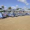 Spiaggia sabbiosa con lettini e ombrelloni.