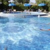 Due piscine con nuotatori e ombrelloni in lontananza.