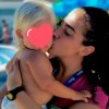 Persona abbraccia e bacia un bambino, vicino a una piscina.