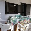 Tavolo con tovaglia a fiori e sedie bianche in terrazza.