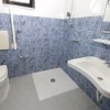 Bagno con piastrelle blu, WC e lavandino.