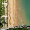 Spiaggia sabbiosa con ombrelloni gialli vista dall'alto.