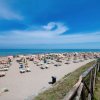 Una spiaggia sabbiosa con una scogliera a sinistra e il cielo blu sopra.
