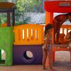 Bambini che giocano su una struttura gioco colorata all'aperto.