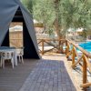 Tenda con terrazza di legno, vista piscina e ulivi.
