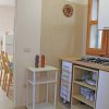 Cucina con sportelli bianchi e tavolo in fondo.