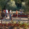 Persone che giocano a bocce in un campo all'aperto circondato da alberi.