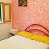 Camera da letto con pareti rosa, letto matrimoniale, e finestrella aperta.