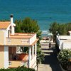 Case vicino al mare, alberi verdi e cielo blu.