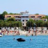 Spiaggia affollata davanti a un grande hotel.