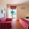 Camera con divano rosso, letto, TV e balcone.
