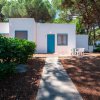 Casa bianca con porta blu tra gli alberi.