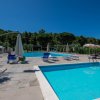 Piscina con sedie a sdraio e ombrelloni, cielo blu.