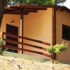 Bungalow con tettoia in legno, circondato da alberi e vegetazione.
