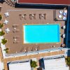 Vista aerea di una piscina con lettini e tavolini.