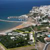 Vista aerea di una cittadina costiera con porto e spiaggia.